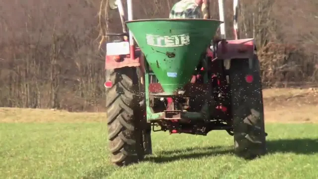 Traktor mit Zentrifugalstreuer fährt beim Kalken frontal auf die Kamera zu